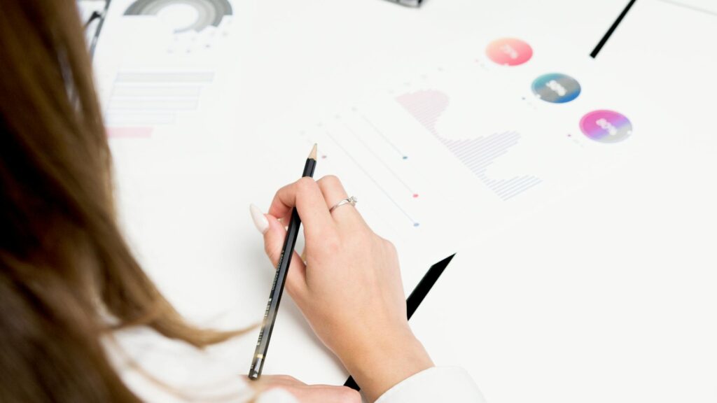 A woman reviews colorful financial charts with a pencil, focusing on growth and data analysis.